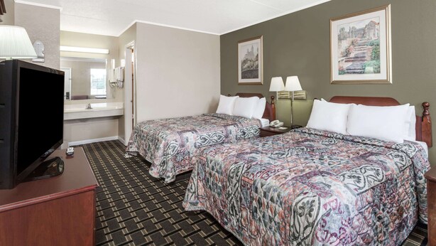 Habitación de hotel con dos camas, televisión, escritorio y baño.