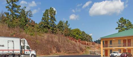 A motel with a green roof, a parking lot, and a truck parked in front.