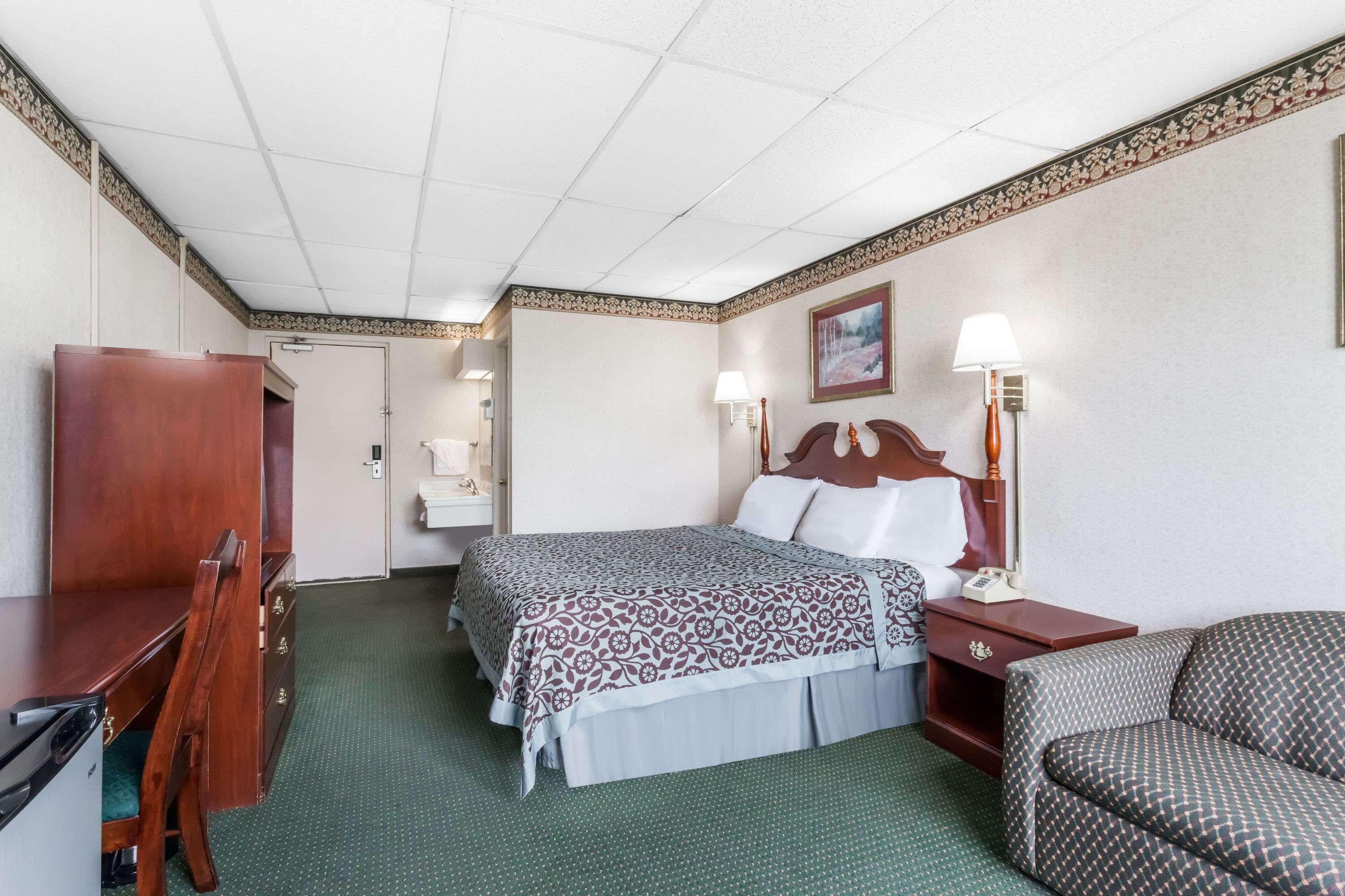 Una habitación de hotel con cama, mesitas de noche, escritorio, silla y armario.