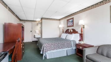 A hotel room with a bed, bedside tables, a desk, a chair, and a wardrobe.