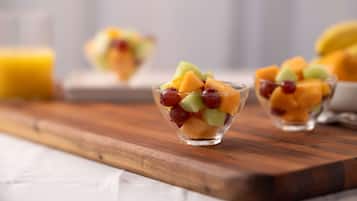 Una tabla de madera con tres recipientes de vidrio que contienen una ensalada de frutas.