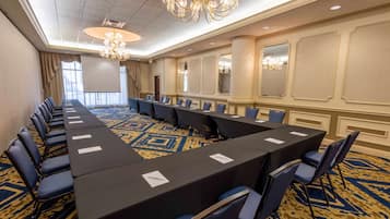 A conference room with a long table, blue chairs, and a patterned carpet.