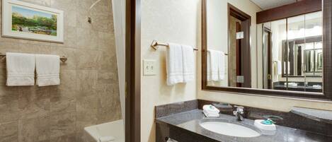 A bathroom with a marble wall, a large mirror, a sink, and a bathtub.