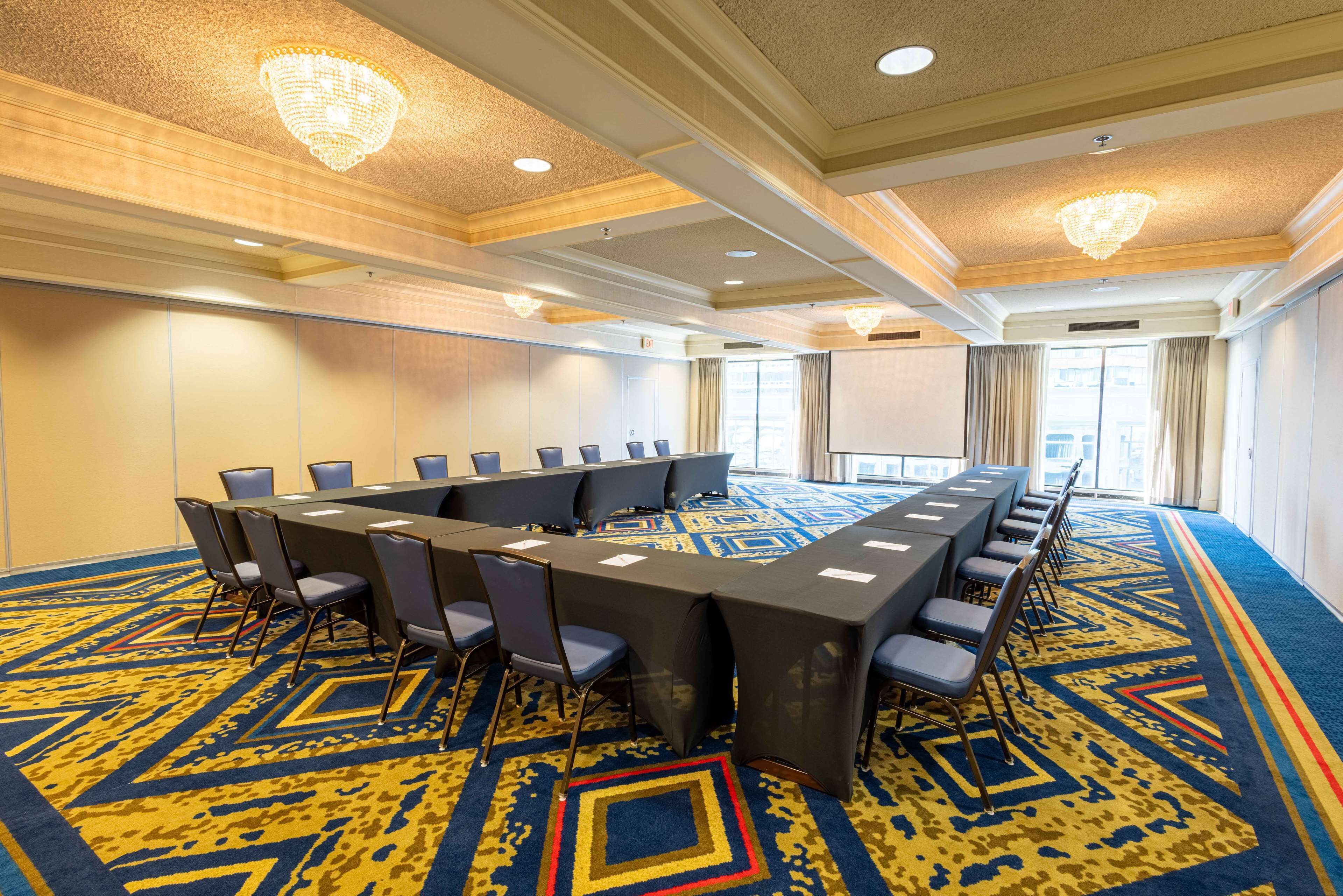 Une salle de conférence avec une longue table, des chaises et un tapis à motifs.