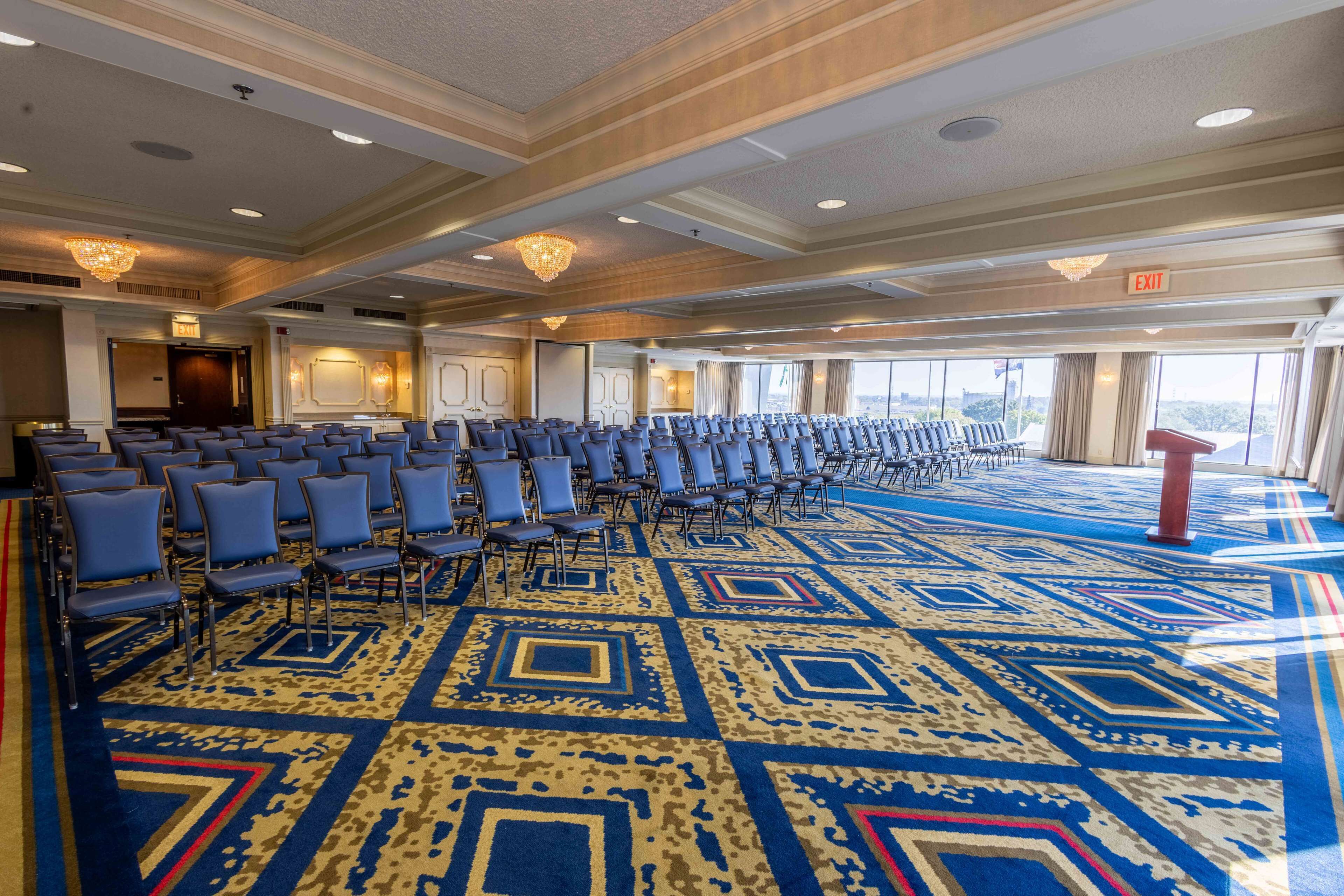 A large conference room with rows of chairs, a patterned carpet, and a chandelier.