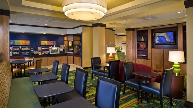 A hotel lobby with seating areas, a bar, and a television screen. - Fairfield Inn & Suites Dulles Airport Chantilly (Chantilly)