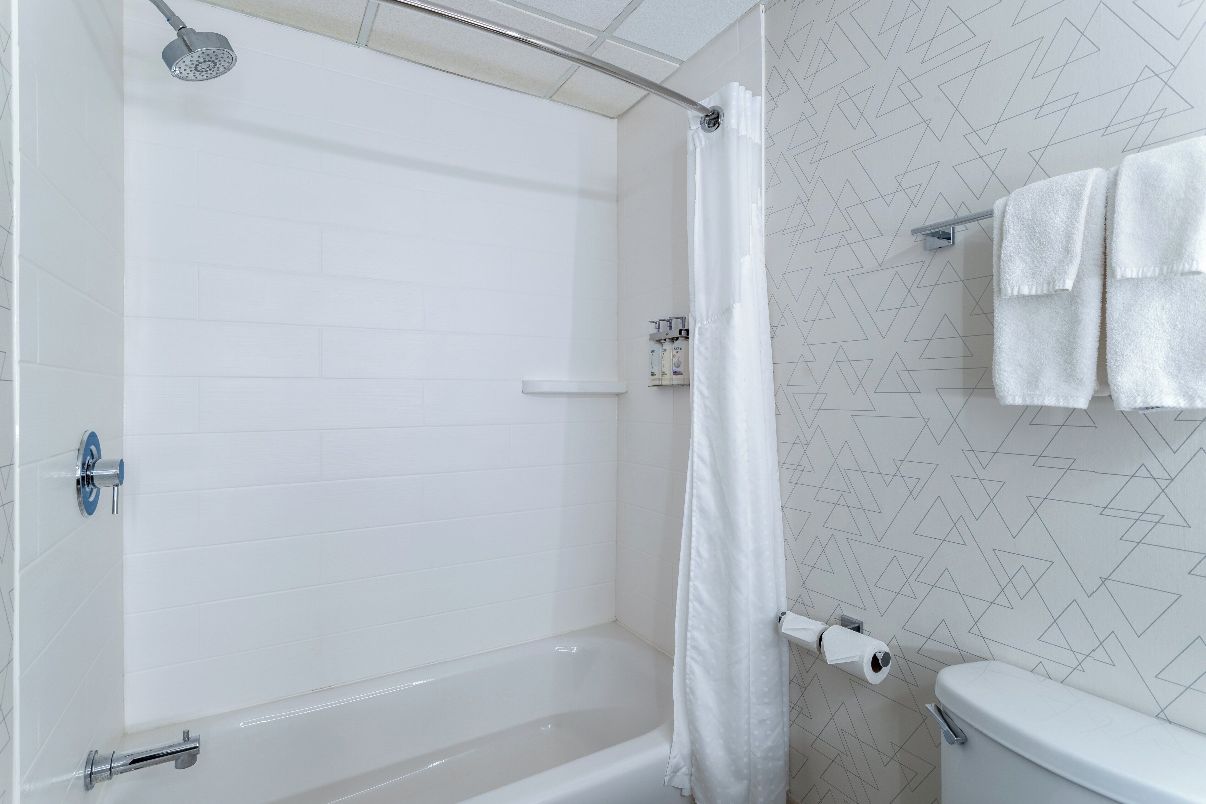 Un baño con ducha, inodoro y toallero.