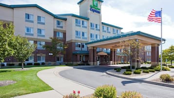 Un hotel Holiday Inn Express con un patio central, una bandera y un césped cuidado.