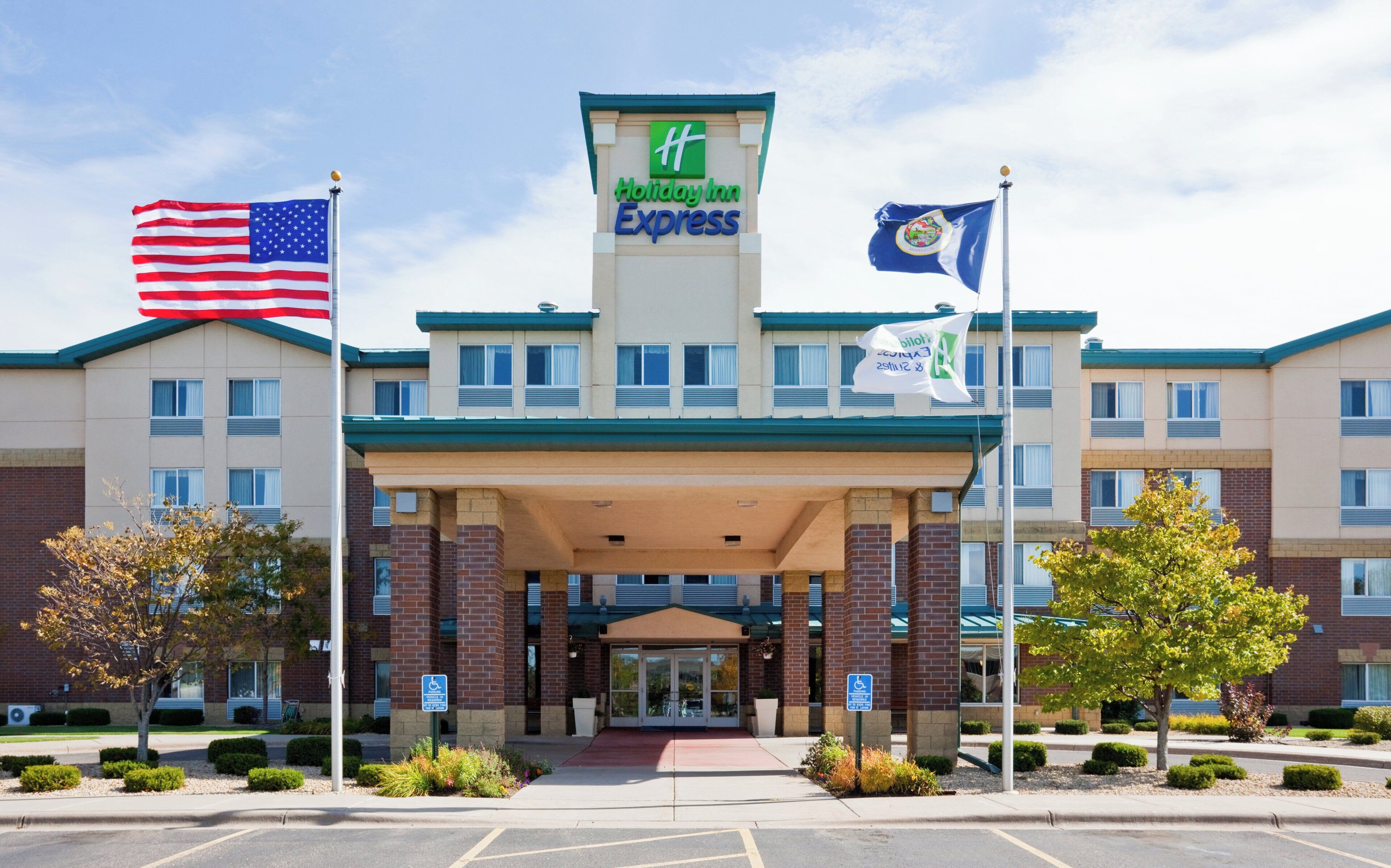 Een Holiday Inn Express gebouw met een bakstenen gevel, een centrale ingang en een parkeerplaats.
