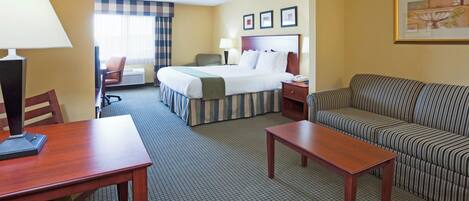 A hotel room with a bed, a sofa, a desk, and a chair.