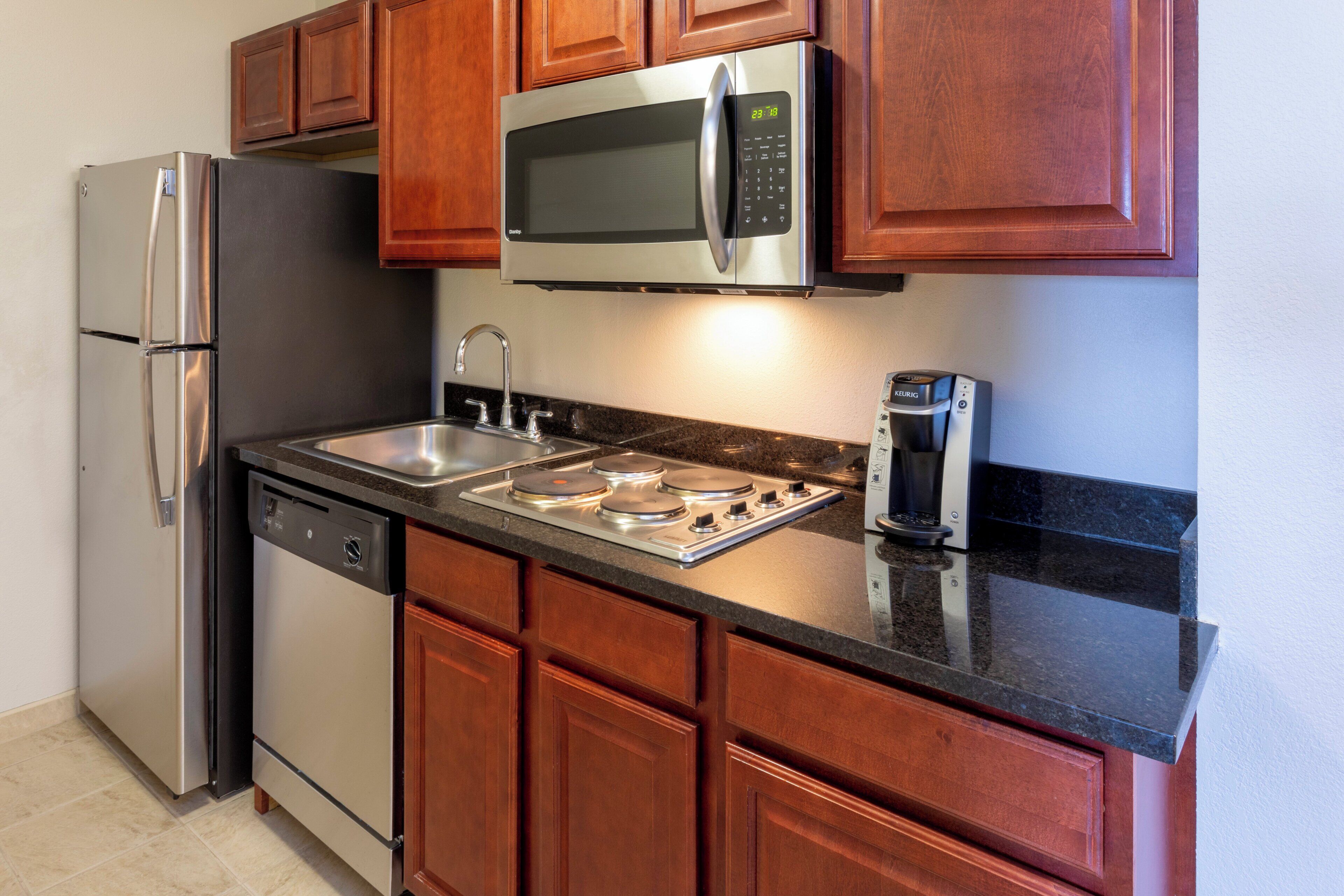 A kitchen with stainless steel appliances, wooden cabinets, a double sink, and a built-in microwave.