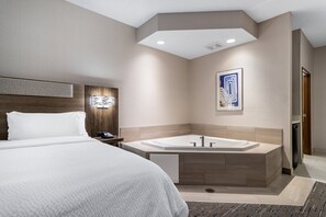Una habitación de hotel moderna con una cama grande, una bañera integrada y un cabecero de madera.