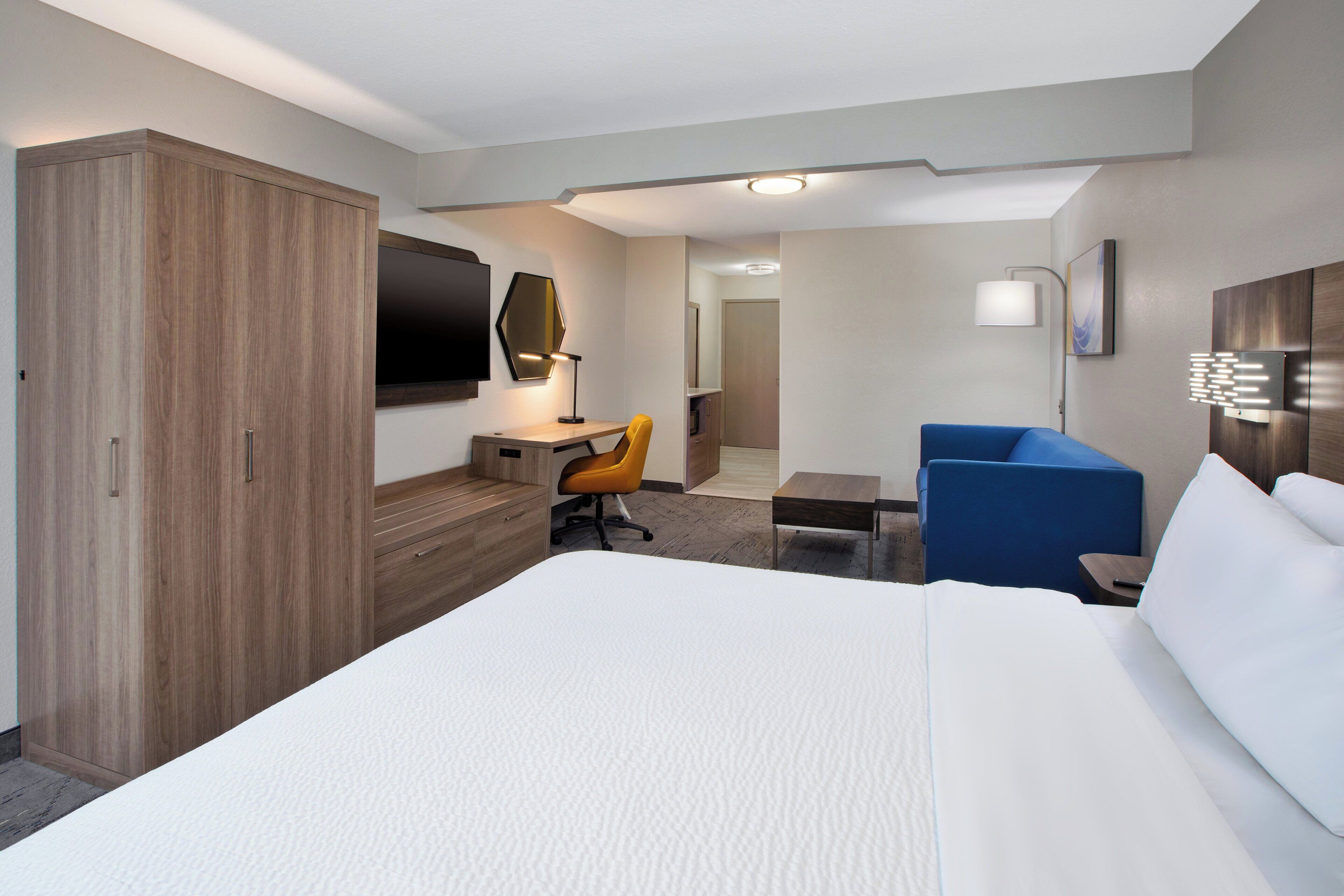Una habitación de hotel con una cama grande, un escritorio, una silla, un armario y una televisión.