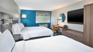 Une chambre d’hôtel avec deux lits, un bureau, une chaise, une télévision et une armoire.