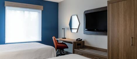 A hotel room with two beds, a desk with a chair, a TV, and a wardrobe.