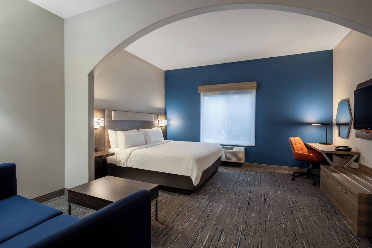 Ein Hotelzimmer mit Bett, Schreibtisch, Stuhl, Fernseher und Fenster.