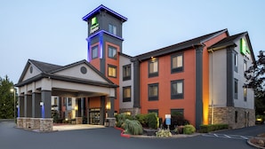 A Holiday Inn Express hotel with a prominent tower, a covered entrance, and a well-maintained outdoor area with landscaping.