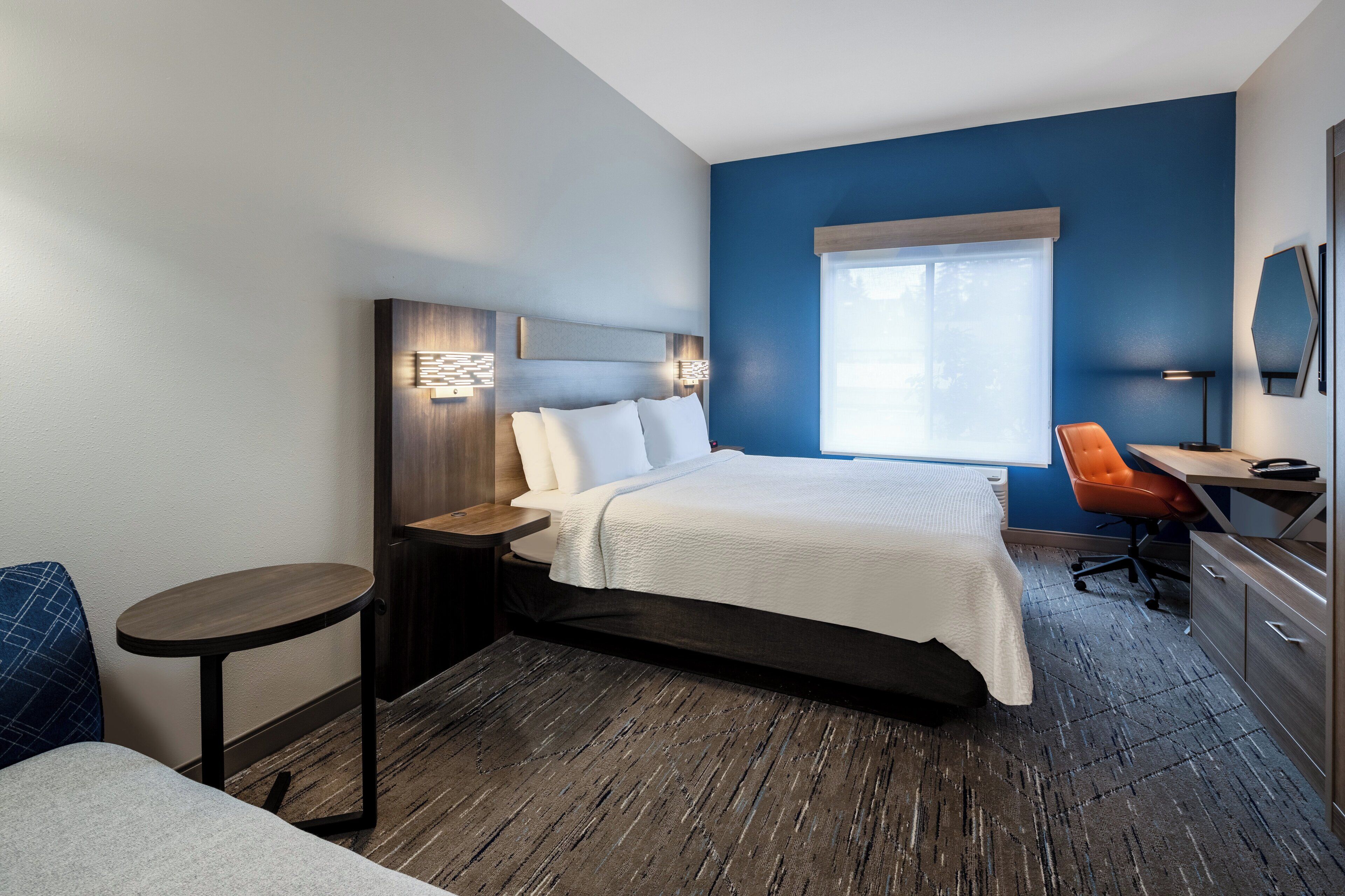 Una habitación de hotel moderna con una cama grande, un escritorio y una silla.