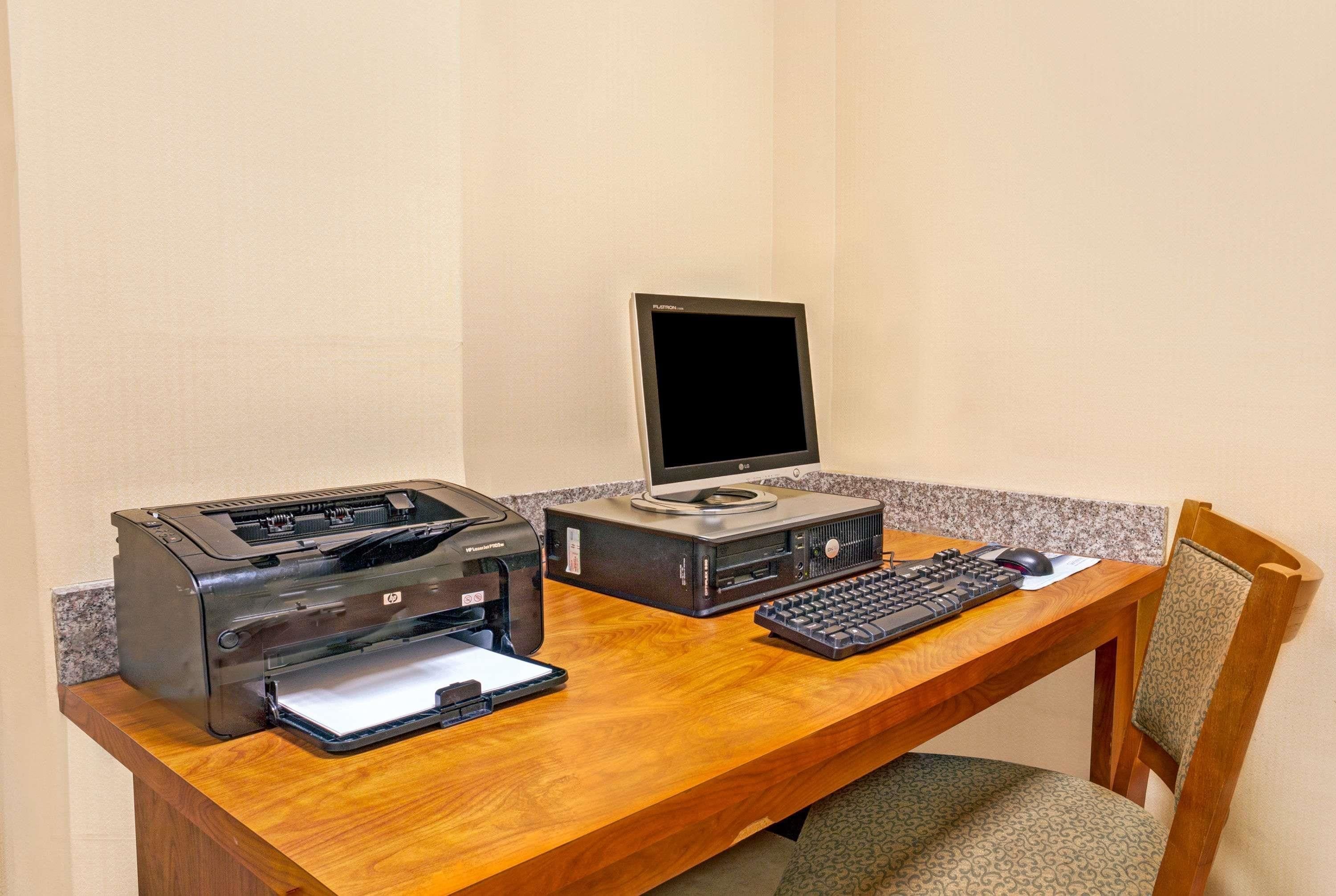 Un bureau en bois avec une imprimante, un écran d’ordinateur et un clavier.