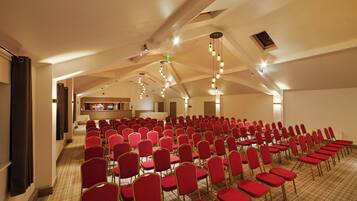 A conference room with rows of red chairs and a kitchenette in the background.