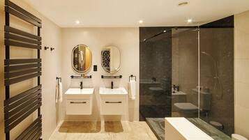 A modern bathroom with two sinks, a glass-enclosed shower, and a wooden towel rack.