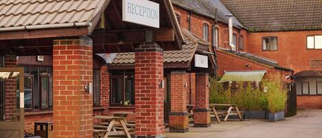 A reception area with a sign, brick pillars, and a tiled roof.