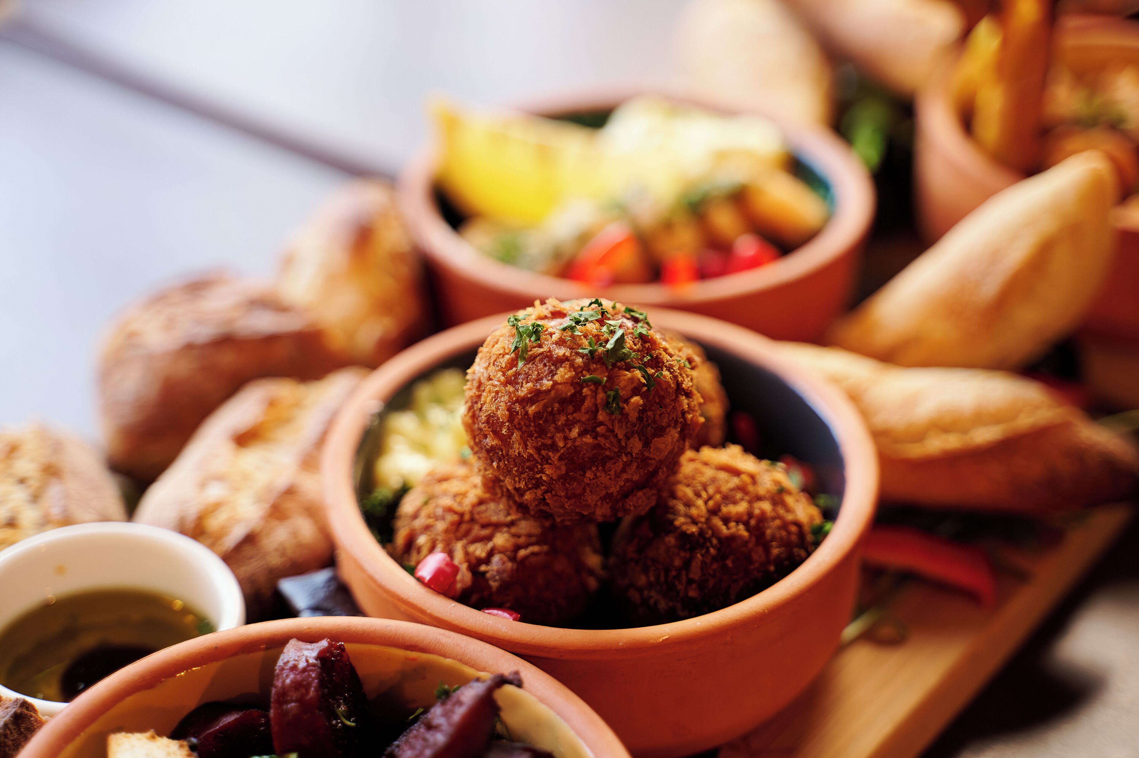 A variety of food items including bread, a bowl of what appears to be a meat dish, and a small bowl of sauce.