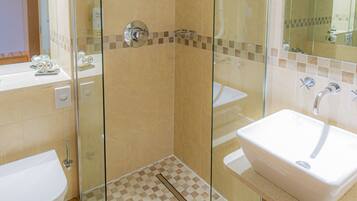 A modern bathroom with a glass-enclosed shower, two sinks, and a large mirror.