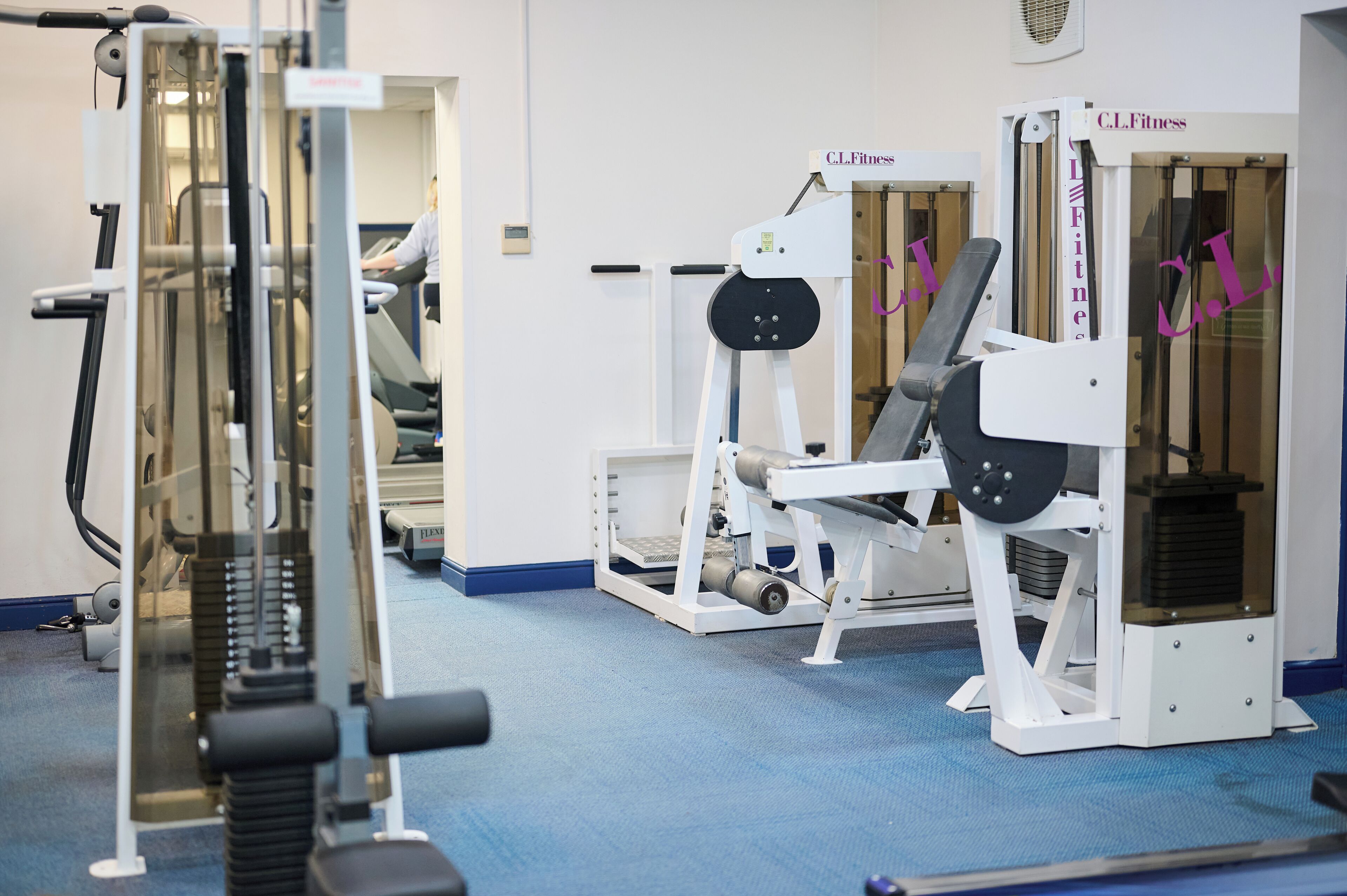 A gym with various exercise machines, including a treadmill and weight machines.