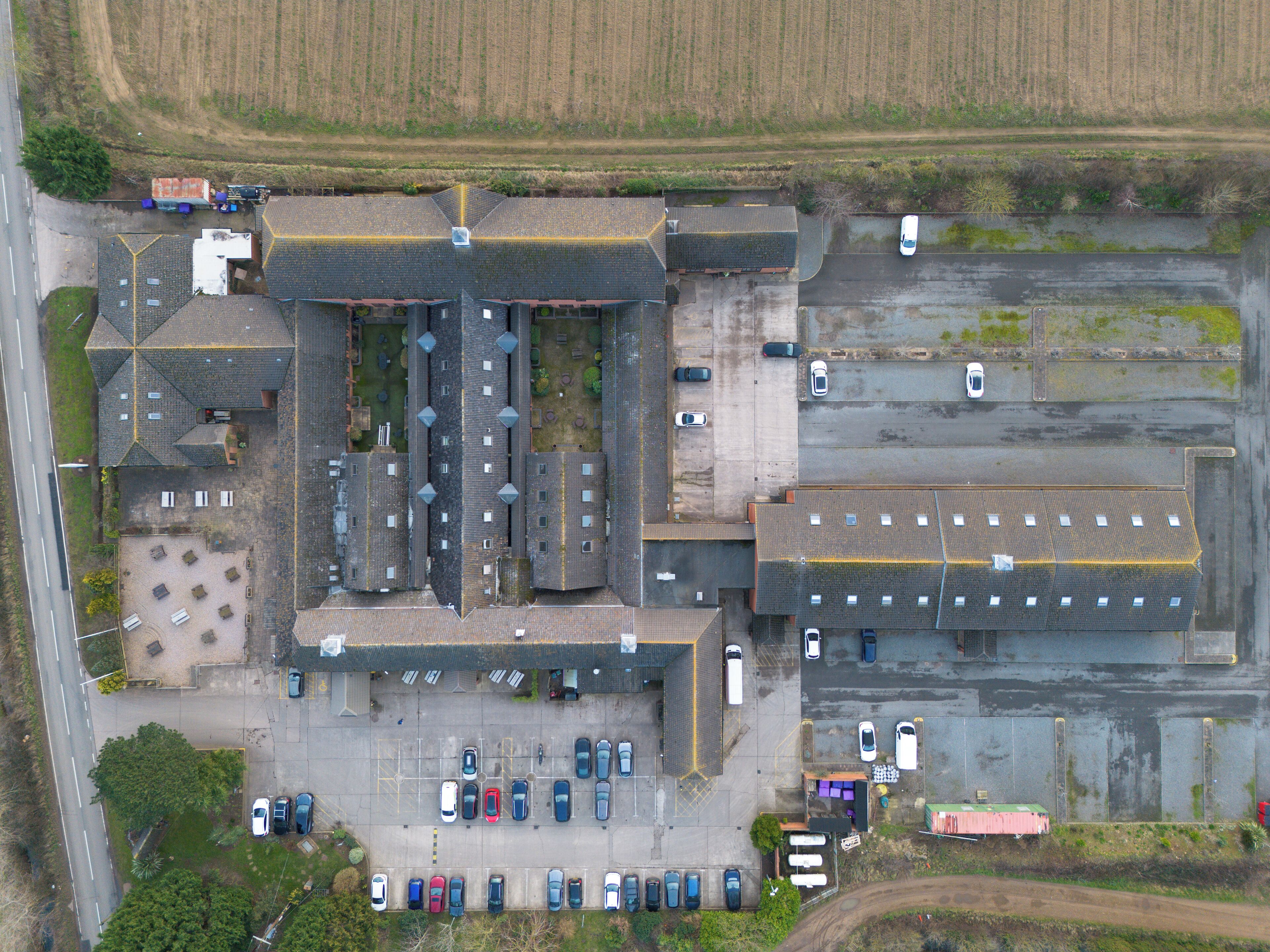 An aerial view of a large industrial building with multiple parking areas and a central courtyard.