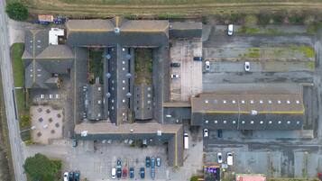 An aerial view of a large industrial building with multiple parking areas and a central courtyard.