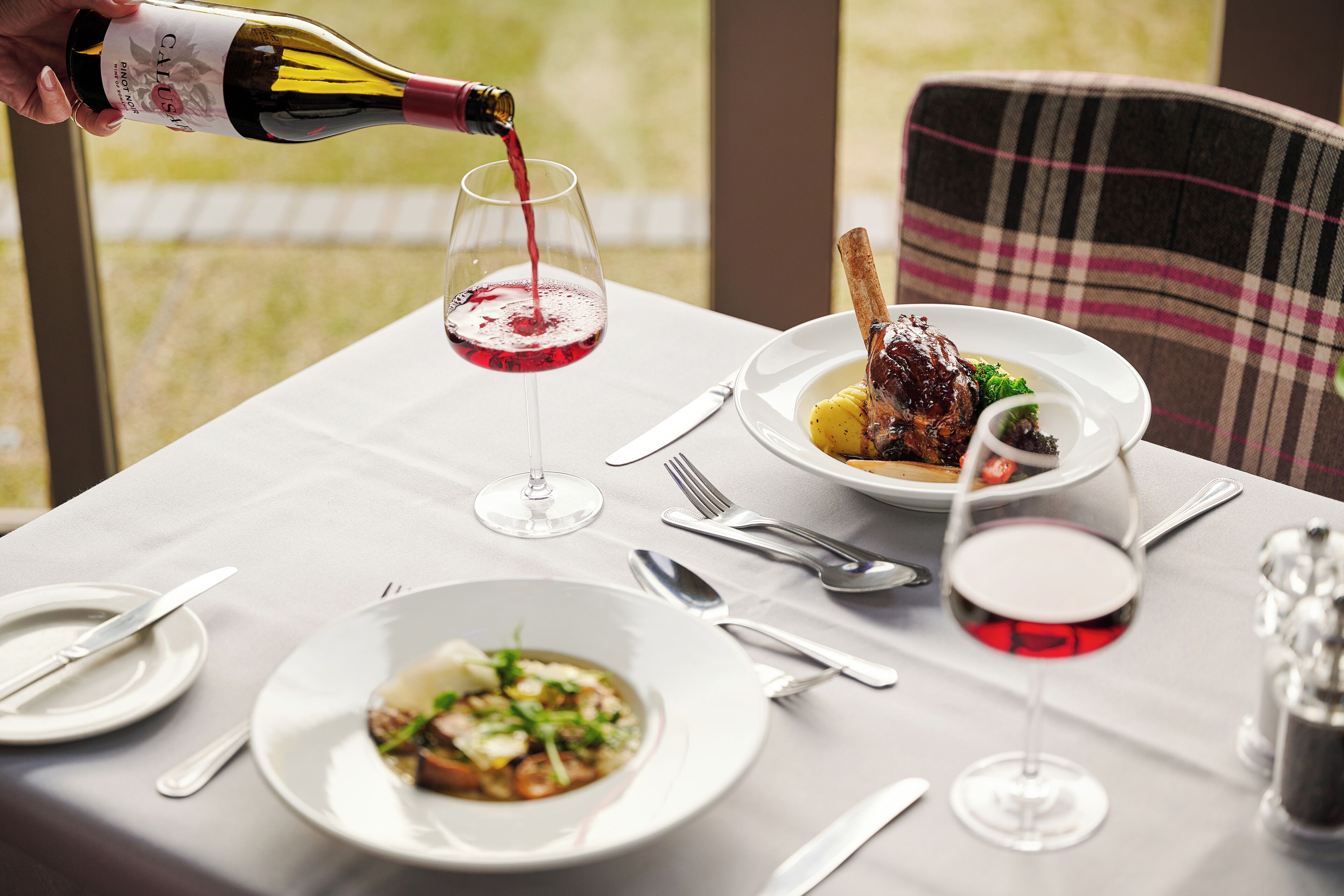A table set for a meal with wine glasses, plates, and cutlery.