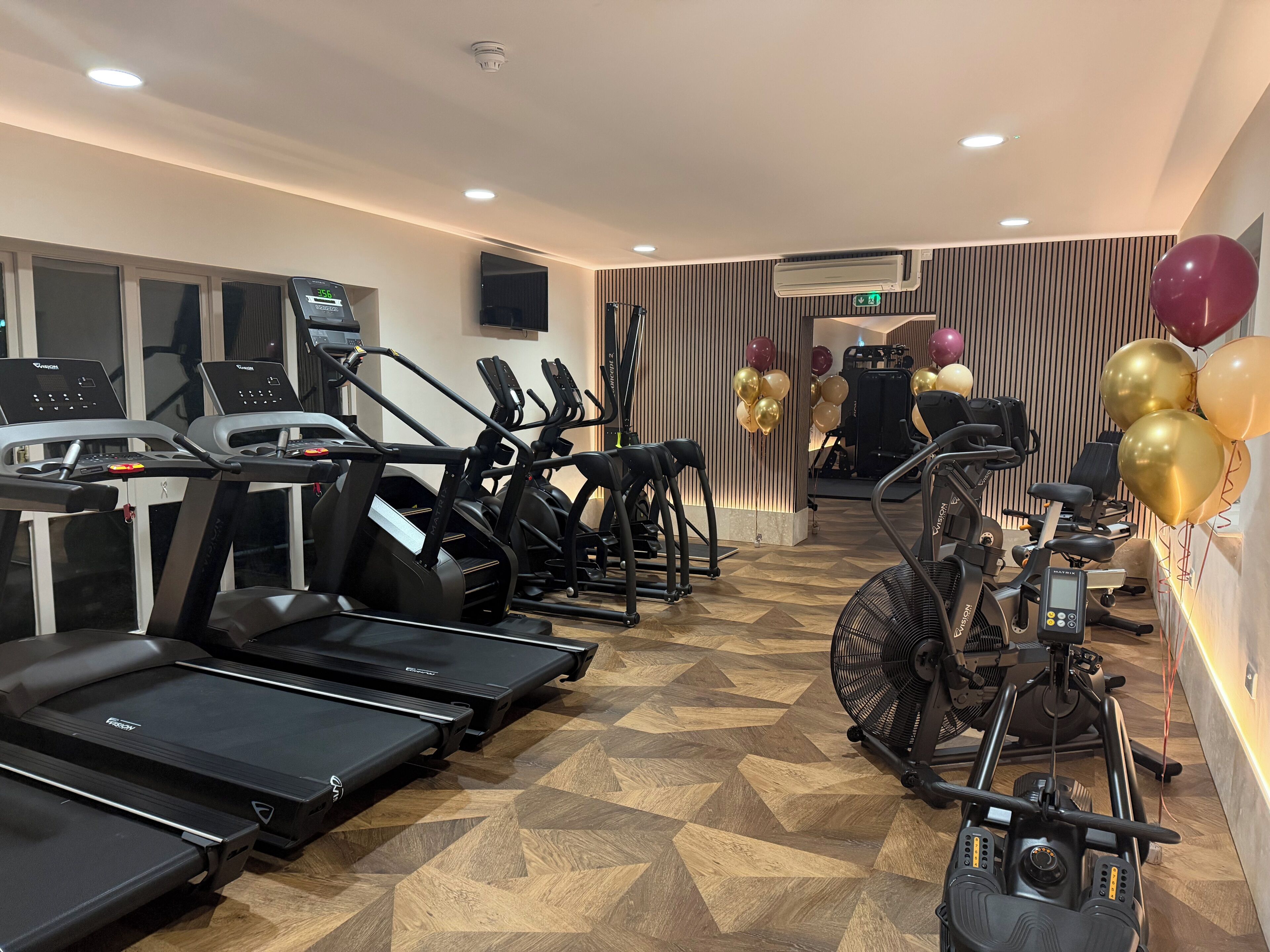 A gym with treadmills, elliptical machines, and a stationary bike.