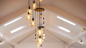 Une salle de banquet avec des tables rondes dressées pour le repas, des lustres et un mur décoré de fleurs.