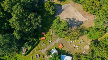 Vista aérea de un camping con varias tiendas de campaña, un espacio de estar circular y un edificio pequeño.
