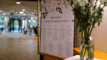 Un panneau d’affichage présentant un menu floral dans le hall d’un hôtel, avec un vase de fleurs posé sur une table.