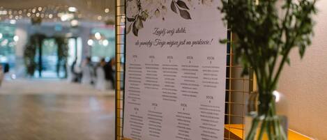 A floral menu board in a hotel lobby with a vase of flowers on a table.