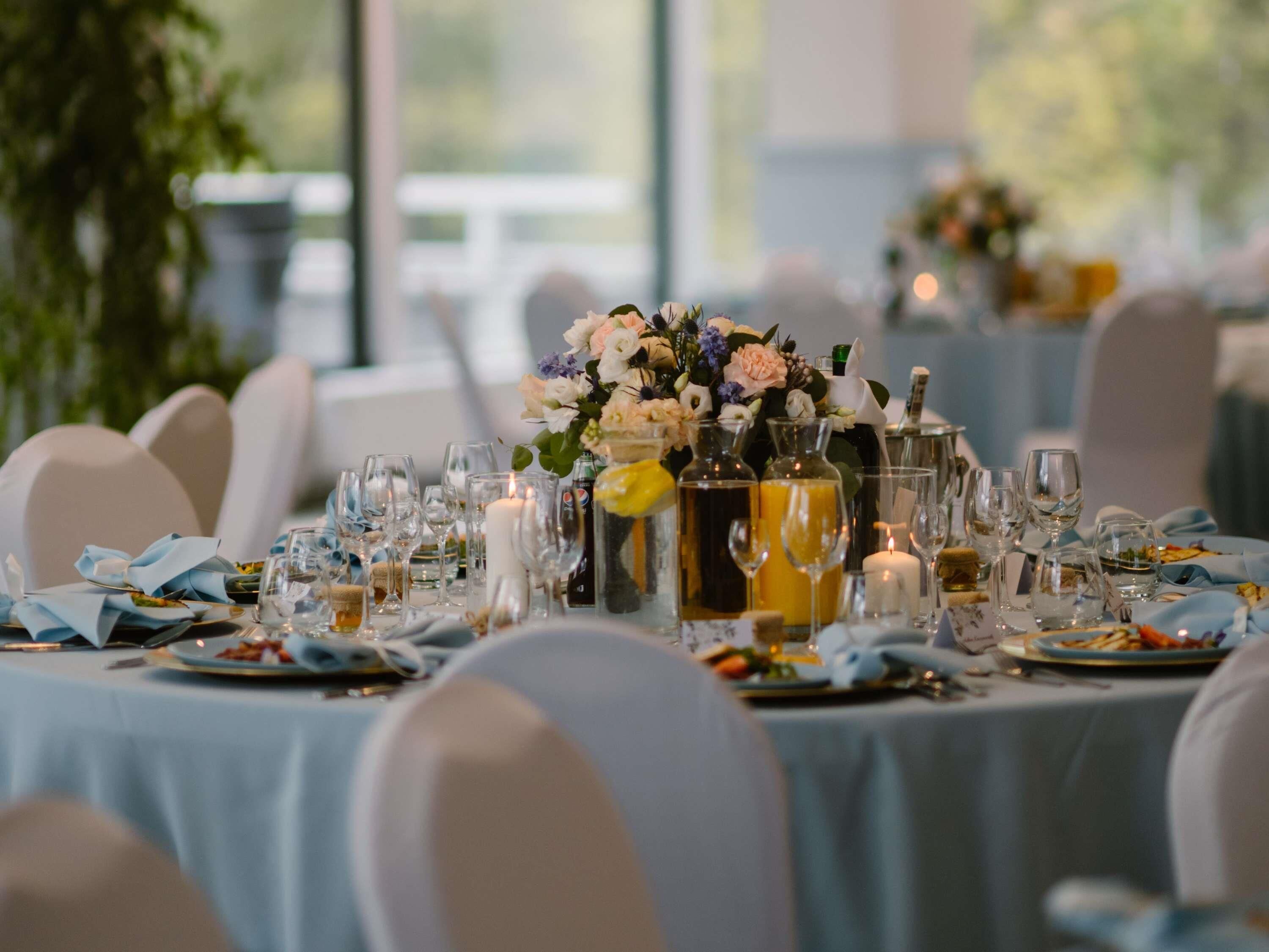 A table set for a meal with glasses, candles, and a floral centerpiece.