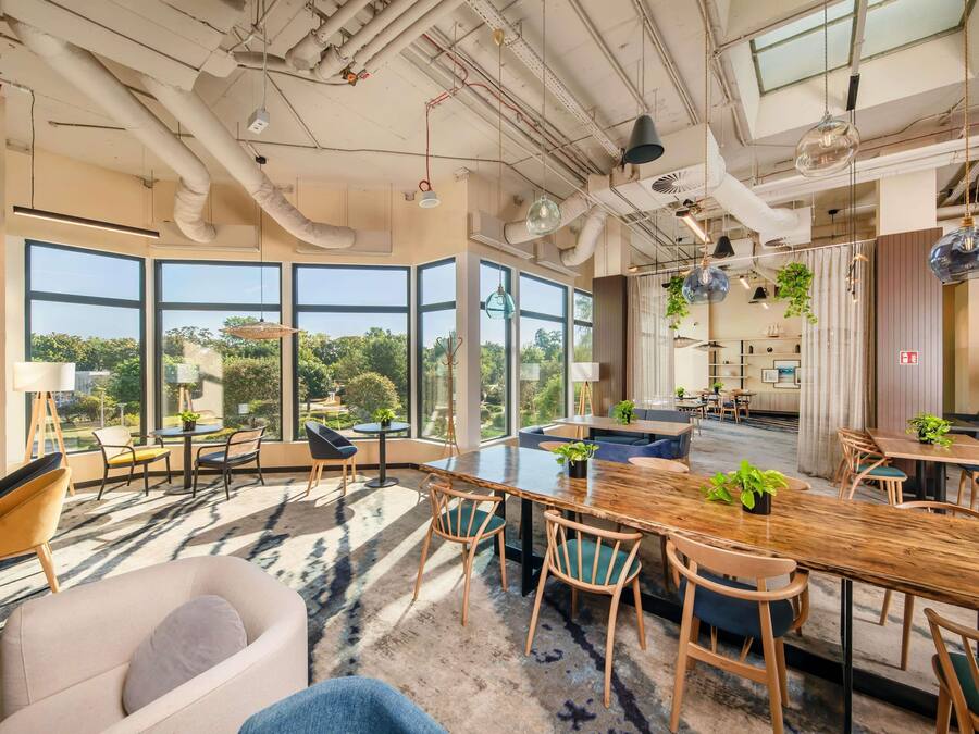 A modern interior with large windows, a central dining area, and a mix of seating arrangements.