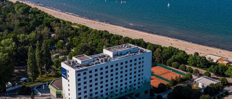 Un hotel con terraza en la azotea, aparcamiento y vistas a la playa y al mar.