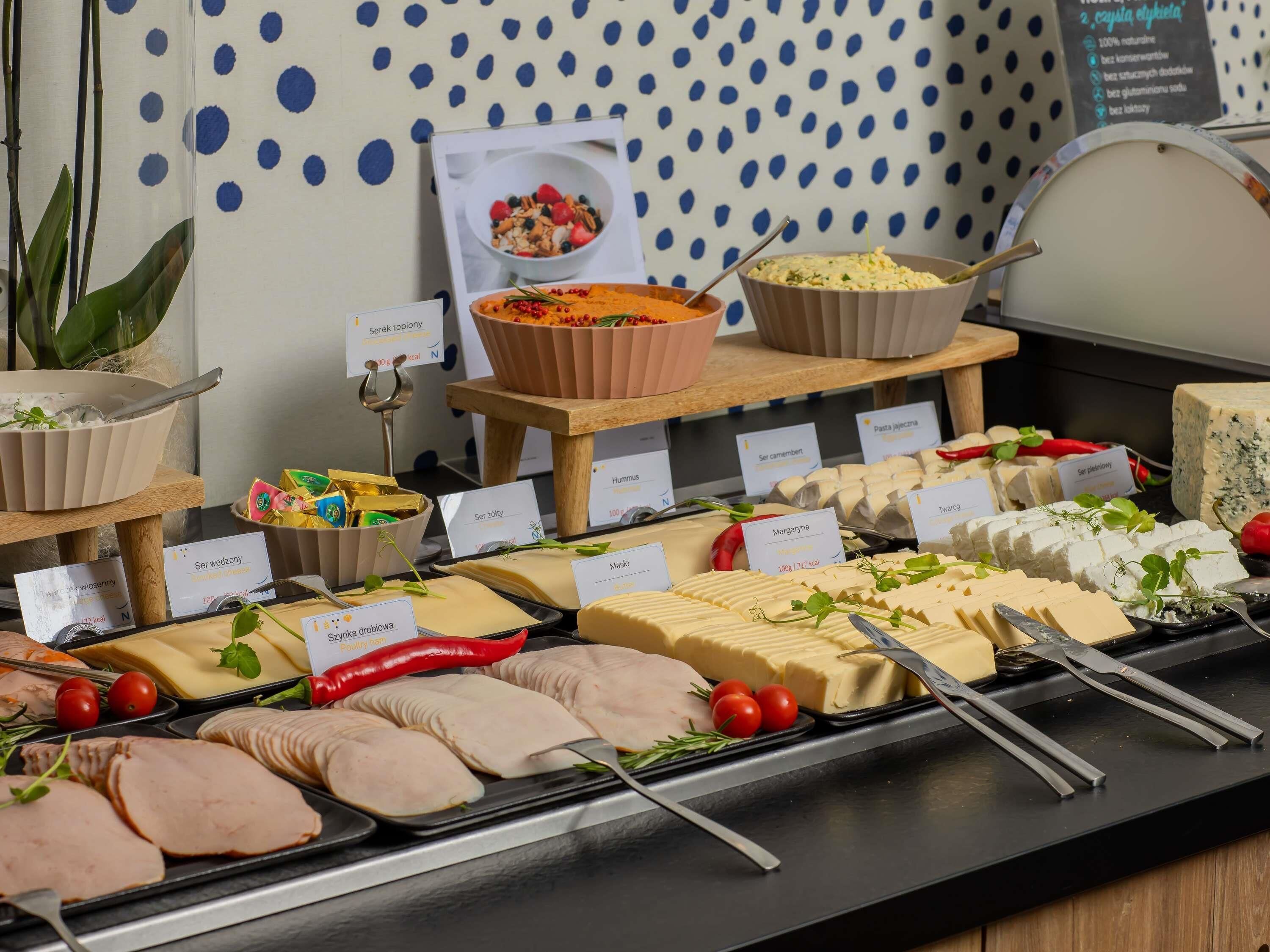 A buffet with various food items including meats, cheeses, and a bowl of salad.