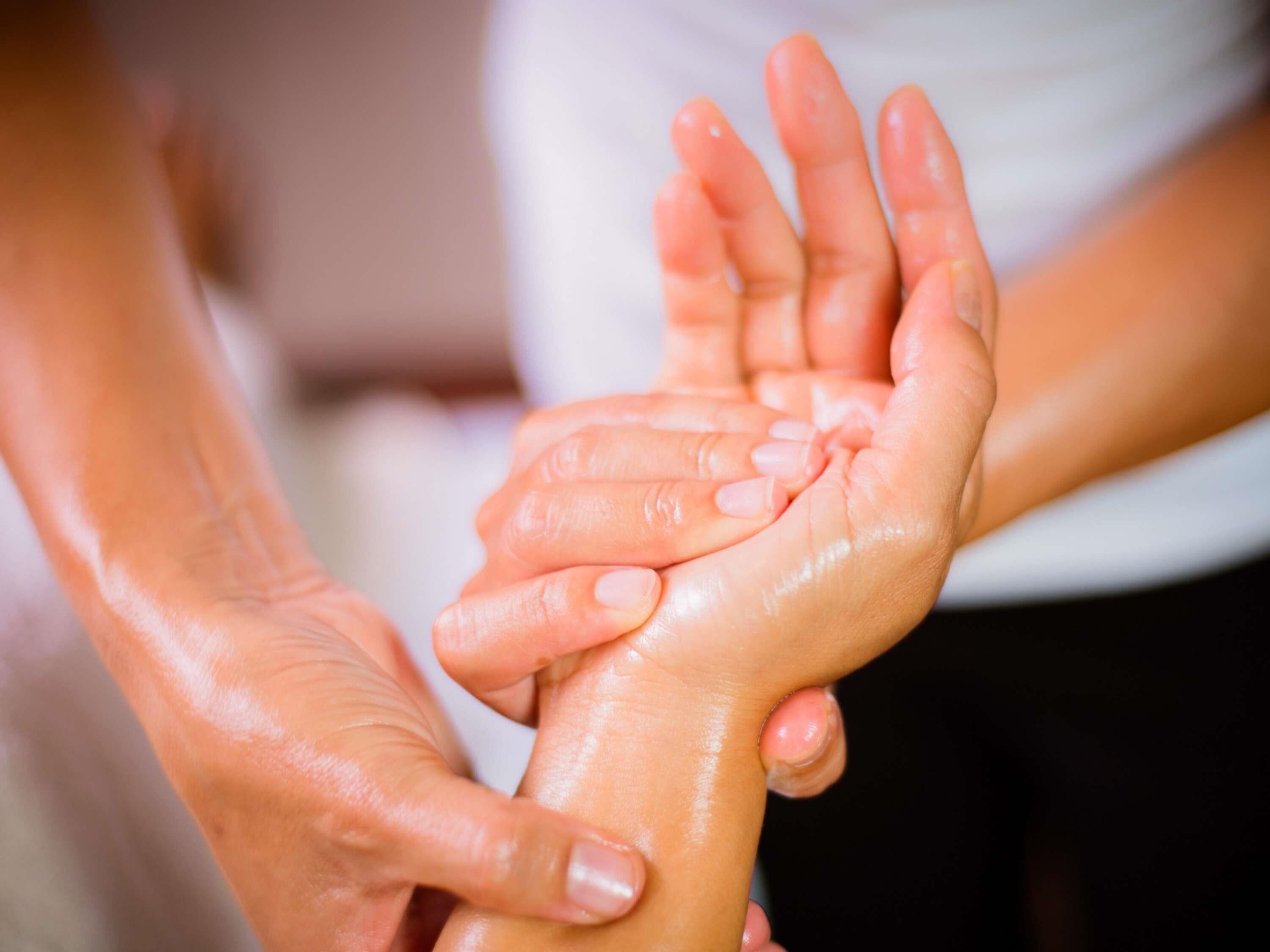 A close-up of hands, one holding the other, with a focus on the fingers and palms.