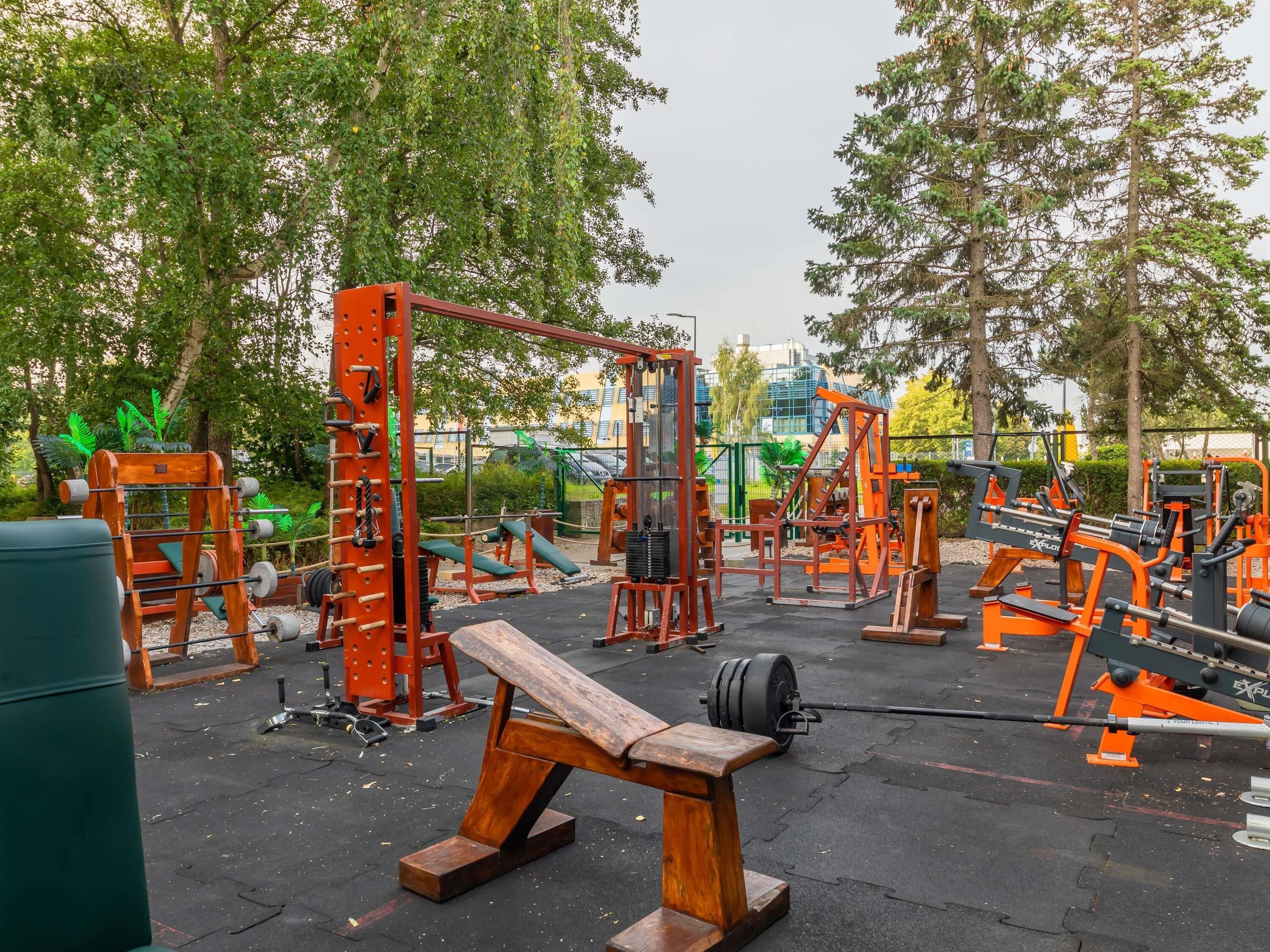 An outdoor gym with various exercise equipment, including benches and weightlifting stations.