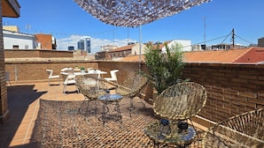A rooftop terrace with a patterned floor, outdoor furniture, and a decorative canopy. - Apartamentos G3 Galeón (Madrid)