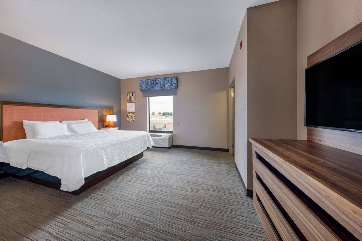 Quarto de hotel com cama, televisão, janela e vista para a cidade.