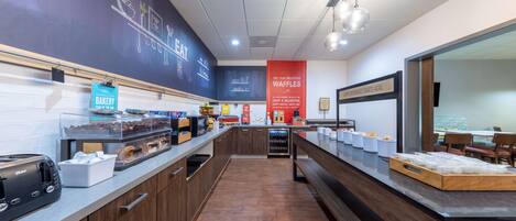 A bakery counter with various baked goods and a sign indicating the location of group breakfast.