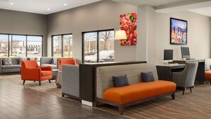 A modern hotel lobby with a seating area, a desk, and large windows offering a view of the outside. - La Quinta Inn & Suites by Wyndham St Louis Route 66 (St. Louis)