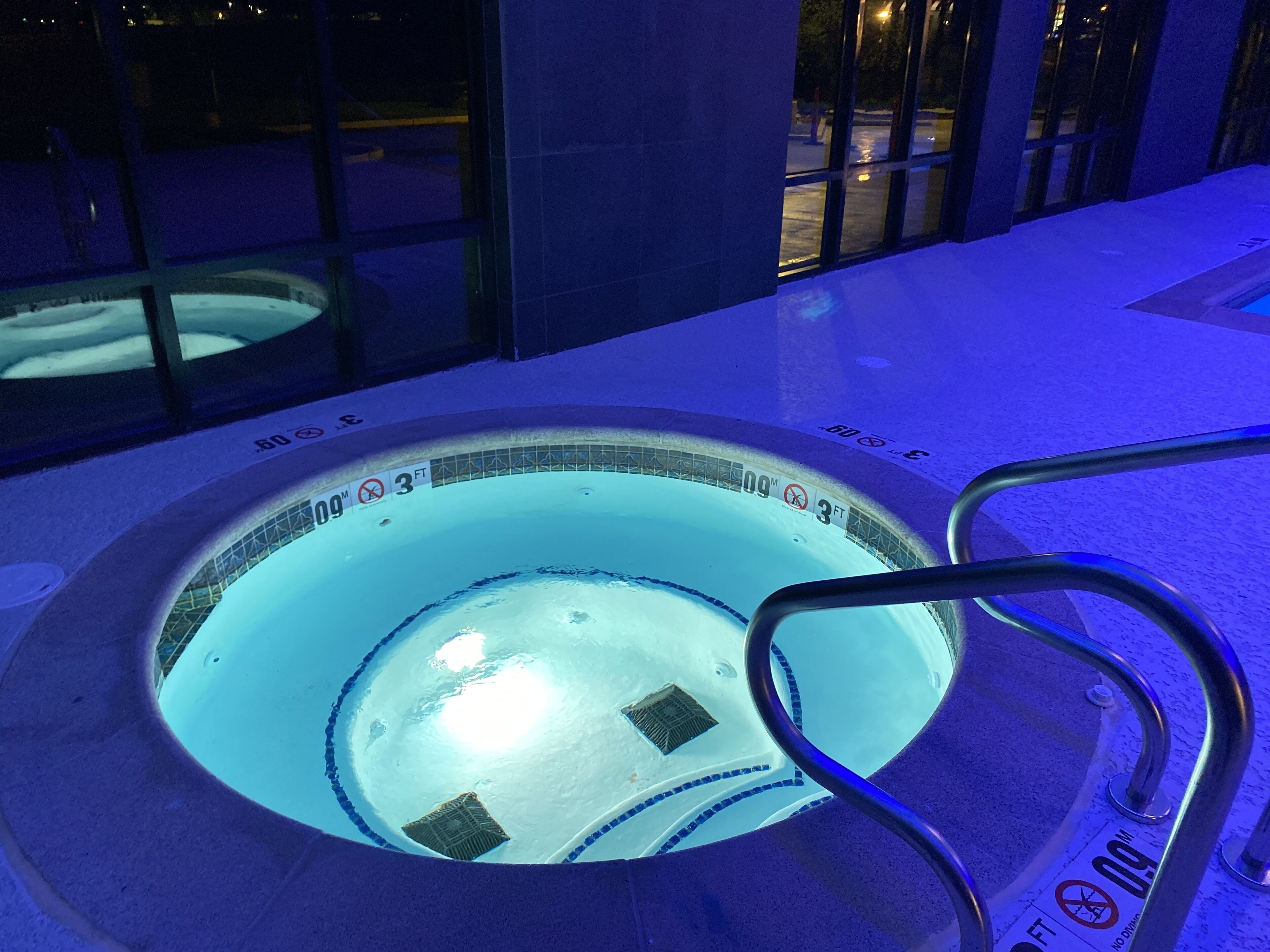 Un jacuzzi con una profundidad de 3 pies y un diámetro de 9 pies, rodeado por una terraza de baldosas.
