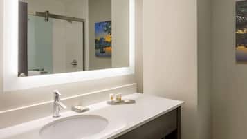 Un baño moderno con un espejo grande, un lavabo blanco y una cabina de ducha de vidrio.