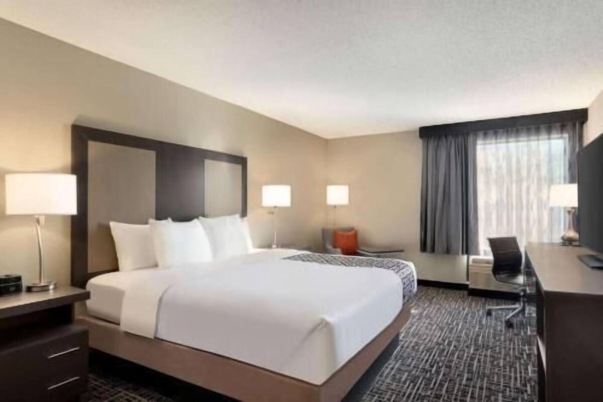Une chambre d’hôtel avec un grand lit, des lampes de chevet, un bureau et une chaise.